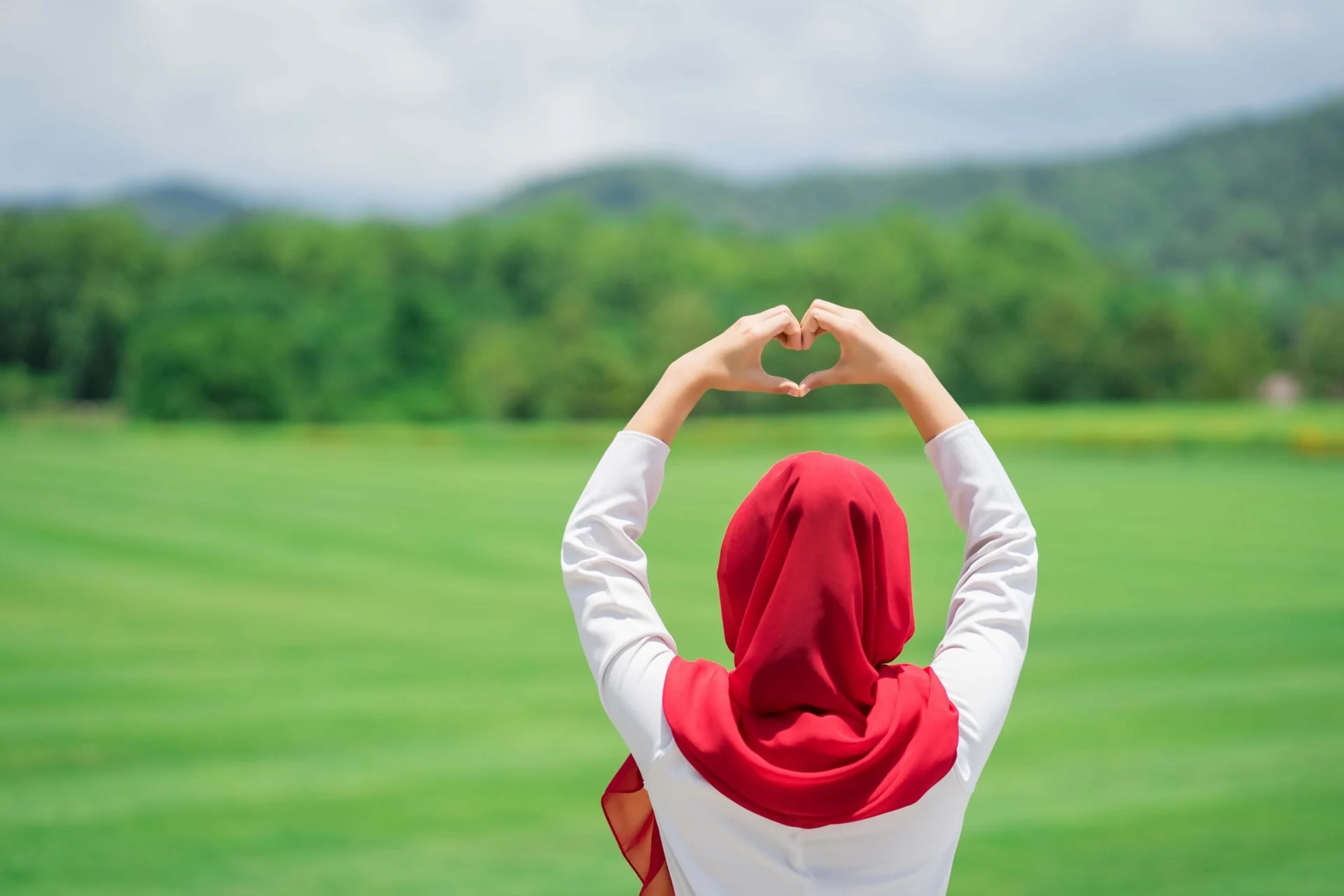 Portrait of happy young muslim red hijab at the green field.